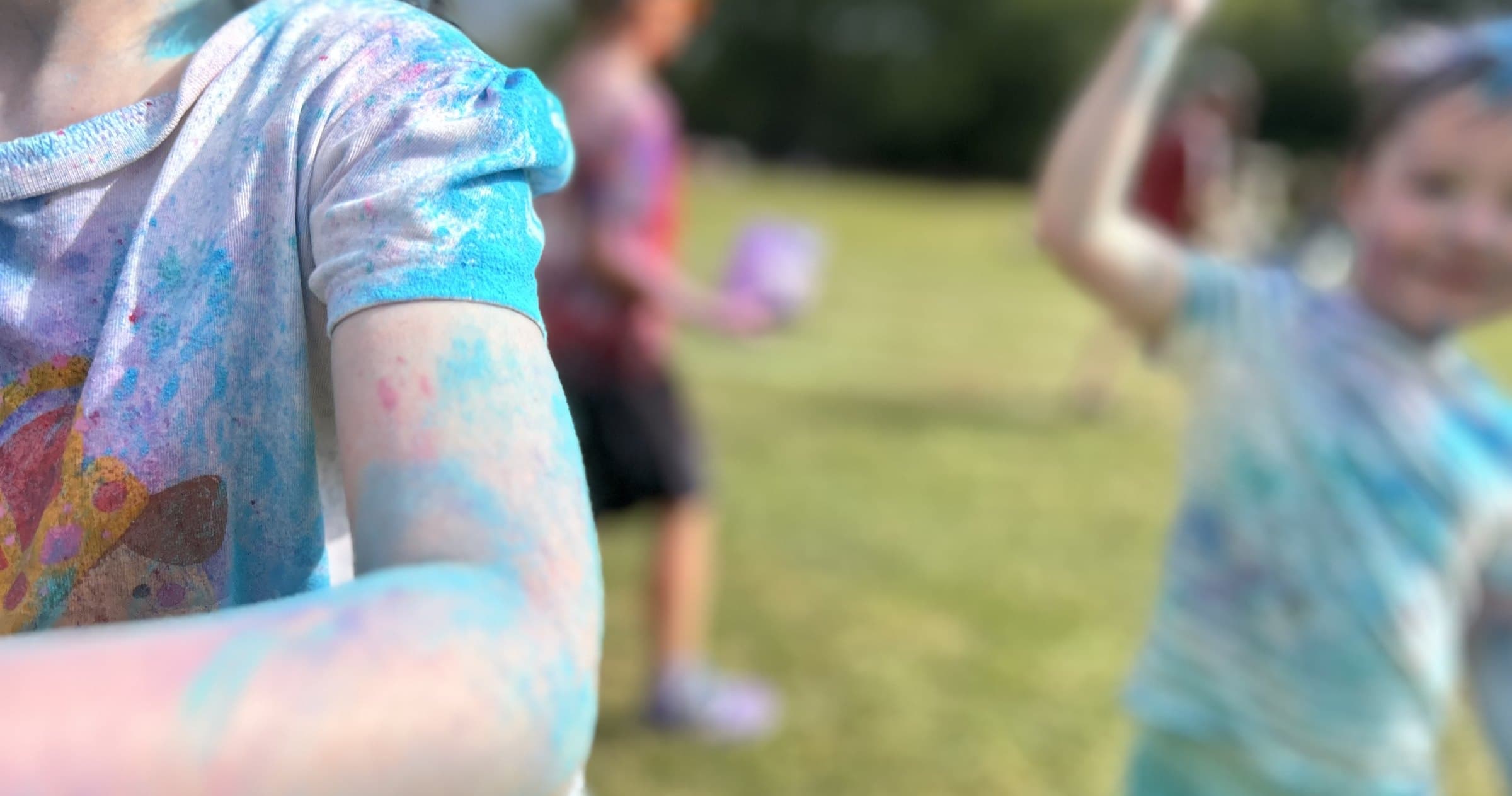 Children covered in coloured powder on a school field at a colour run